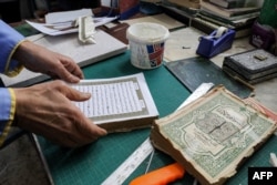 A man assembles pages together to be glued into a volume during a workshop on the restoration of copies of the Holy Koran, Islam's holy book, in Libya's capital Tripoli on March 22, 2022. (Photo by Mahmud Turkia / AFP)