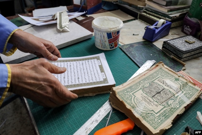 A man assembles pages together to be glued into a volume during a workshop on the restoration of copies of the Holy Koran, Islam's holy book, in Libya's capital Tripoli on March 22, 2022. (Photo by Mahmud Turkia / AFP)