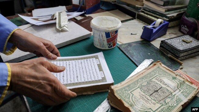 Seorang pria tampak menyusun halaman Al-Quran menjadi satu dalam pelatihan restorasi Al-Quran lama di Tripoli, Libya, pada 22 Maret 2022. (Foto: AFP/Mahmud Turkia)