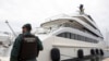 Seorang petugas sipil berdiri di dekat kapal pesiar "Tango" di Palma de Mallorca, Spanyol, Senin 4 April 2022. (AP/Francisco Ubilla)