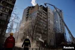 Tim penyelamat bekerja di sebelah gedung apartemen yang terkena tembakan, saat serangan Rusia di Ukraina berlanjut, di Kyiv, Ukraina 16 Maret 2022. (Foto: REUTERS/Thomas Peter)