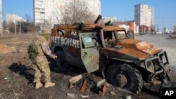Binh sĩ Ukraine bên cạnh 1 xe chở quân của Nga bị tiêu diệt ở gần Kharkiv hôm 24/3.