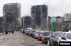 A view shows a line of cars near apartment buildings destroyed during in Russia's invasion of Ukraine, as evacuees leave the besieged port city of Mariupol, Ukraine, March 17, 2022.