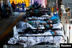 FILE - Patients wearing face masks rest at a makeshift treatment area outside a hospital, following the COVID-19 outbreak in Hong Kong, China, March 2, 2022.