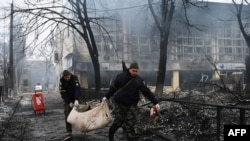 Des policiers ukrainiens retirent le corps d'un passant tué lors d'une frappe aérienne qui a frappé la tour de télévision principale, au cœur de la capitale ukrainienne le 1er mars 2022, en Ukraine. C'est la conséquence de l'invasion de la Russie en Ukraine.