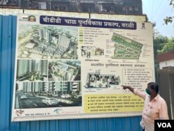 Bhagwan Sawant, a resident of BDD Chawls, looks at a board that showcases the BBD Chawl development including a 500 square foot flat to be given to the occupants. (Anjana Pasricha/VOA)