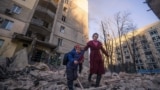 A woman with a child evacuates from a residential building damaged by shelling, as Russia's attack on Ukraine continues, in Kyiv, Ukraine, in this handout picture released March 16, 2022.