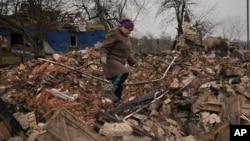 Una mujer busca artículos personales entre los escombros de su casa, destruida durante los combates entre las fuerzas rusas y ucranianas en el pueblo de Yasnohorodka, en las afueras de Kiev, el 30 de marzo de 2022.