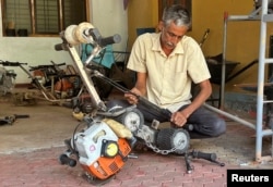 Ganapathi Bhat (50), memeriksa alat buatannya yang bernama "skuter pohon" di rumahnya di Mangaluru, negara bagian Karnataka, India, 19 Februari 2022. (REUTERS/Sunil Kataria)