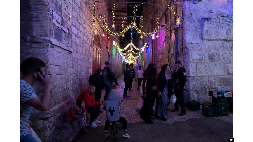 Perempuan bercadar meninggalkan kompleks Masjid Al Aqsa melewati sekelompok polisi Israel pada hari kedua bulan suci Ramadhan di Kota Tua Yerusalem, Minggu, 3 April 2022. (AP Photo/Maya Alleruzzo)