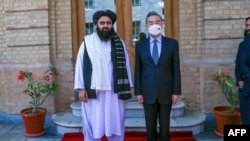 This handout photo released by the Taliban Foreign Ministry shows Taliban Foreign Minister Amir Khan Muttaqi (L) posing with China's Foreign Minister Wang Yi in Kabul on March 24, 2022.