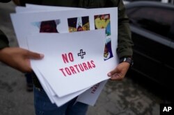 Un manifestante sostiene un cartel pidiendo el fin de la tortura contra prisioneros políticos frente al Servicio Nacional Bolivariano de Inteligencia (SEBIN) en Caracas, Venezuela, el 3 de noviembre de 2021.