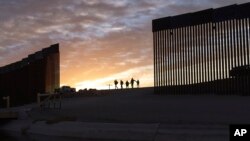 En esta foto de archivo del jueves 10 de junio de 2021, un par de familias migrantes de Brasil pasan por un hueco en el muro fronterizo para llegar a Estados Unidos después de cruzar de México a Yuma, Arizona, para buscar asilo. [Foto de archivo]
