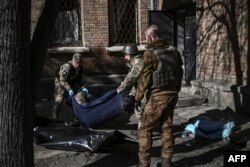Military emergency service members remove the body of a dead Ukrainian serviceman in the area of a research institute, part of Ukraine's National Academy of Science, after a strike, in northwestern Kyiv, March 22, 2022.