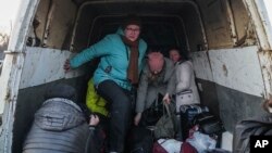 Internally displaced people from Mariupol get out of a van as they arrive at a refugee center in Zaporizhia, Ukraine, March 25, 2022.