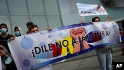 Personas que dicen que sus familiares son víctimas de violaciones de derechos humanos sostienen un cartel que dice en español "¡Di no a la tortura!" frente a la sede del Programa de las Naciones Unidas para el Desarrollo (PNUD) en Caracas, el 29 de octubre de 2021.