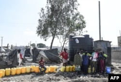 Perempuan membawa jerigen mengantre untuk mendapatkan air di samping kamp darurat mereka, di pemukiman informal Mukuru Kwa Njenga, Kenya, 10 Maret 2022. (Foto: AFP)