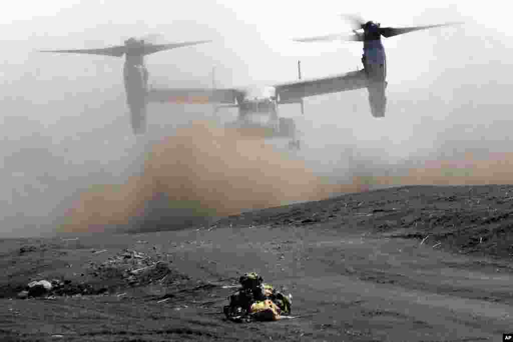 An MV-22 Osprey takes off as one of members of the Japan Ground Self-Defense Force (JGSDF) guards the landing zone during a joint military helicopter-borne operation drill between JGSDF and U.S. Marines at the Higashi Fuji range in Gotemba, southwest of Tokyo.