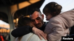 FILE - A Ukrainian refugee says goodbye to his wife and daughter before they board a train for Budapest, having fled from their own country during the Russian invasion, at North Railway Station in Bucharest, Romania, March 14, 2022.