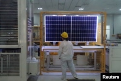 FILE - A worker conducts quality-check of a solar module product at a factory of a monocrystalline silicon solar equipment manufacturer, in Xian, Shaanxi province, China, Dec. 10, 2019.