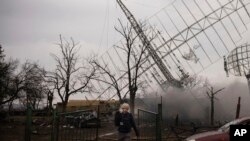 Associated Press videographer Mstyslav Chernov walks amid smoke rising from an air defense base in the aftermath of a Russian strike in Mariupol, Ukraine, Feb. 24, 2022.