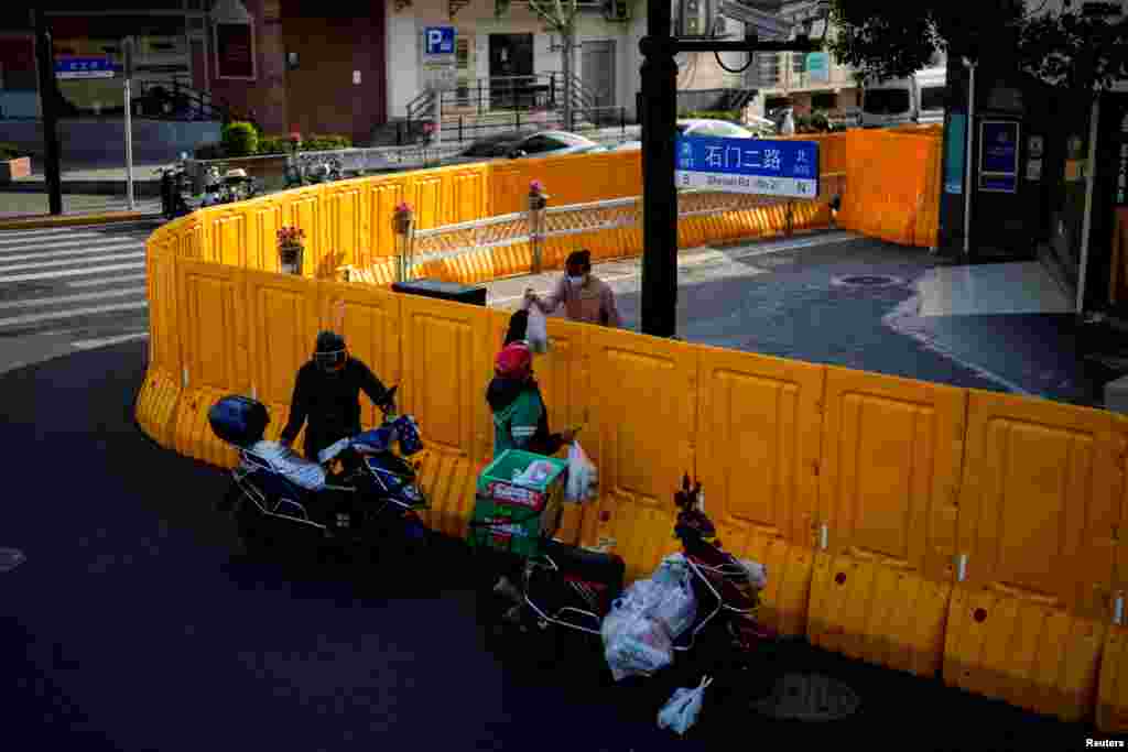 A delivery worker passes food to a woman over the barriers of an area under lockdown amid the COVID-19 pandemic, in Shanghai, China.