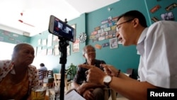 In this photo taken in May 15, 2018, rights activist Le Van Dung (R) live streams on Facebook in a coffee shop in Hanoi, Vietnam. REUTERS/Kham