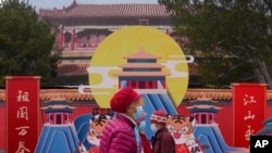 Women wearing masks walk through a park March 18, 2022, in Beijing. 