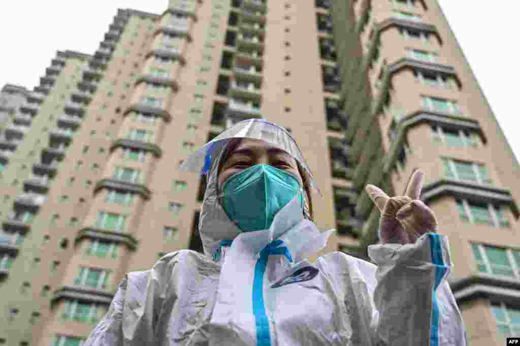 A worker wearing protective gear gestures as people wait to be tested for the Covid-19 coronavirus at a residential compound in Shanghai.