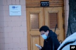 A journalist walks past a sign of the Moscow office of German public broadcaster Deutsche Welle in Moscow, Russia, Feb. 4, 2022.