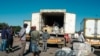 Men wait besides a trailer at the back of a bus that has just arrived in Harare from South Africa 