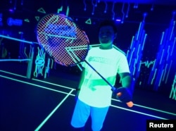 A badminton player shows his glow-in-the-dark badminton racket at a badminton court in Kuala Lumpur, Malaysia, March 24, 2022. (REUTERS/Hasnoor Hussain)