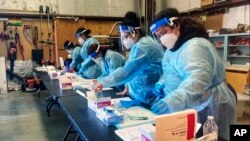 Trabajadoras se toman un descanso después de realizar pruebas diagnósticas de COVID-19 a migrantes que fueron liberados por la Patrulla Fronteriza en el Centro Regional para la Salud Binacional, el 5 de febrero de 2022, en Somerton, Arizona, EE. UU.
