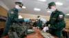 FILE - A Russian officer, left, hands face masks to a conscript at a military conscription office in Moscow, May 22, 2020. 