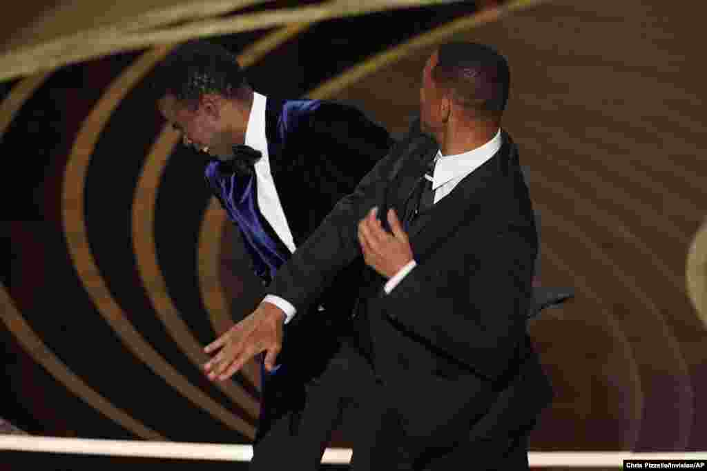 តារា​សម្តែង​អាមេរិក​លោក Will Smith (ខាងស្តាំ) បាន​ទះ​ពិធី​ករ​លោក Chris Rock ​នៅ​លើ​ឆាក​ ពេល​លោក​ថ្លែង​ក្នុង​ពេល​ផ្តល់​ពានរង្វាន់​សម្រាប់​ខ្សែភាពយន្ត​ឯកសារ​ល្អ​បំផុត​របស់​កម្មវិធី​ពានរង្វាន់​អូស្ការ Oscars ​កាលពី​ថ្ងៃទី​ ២៧ ខែ​មីនា ឆ្នាំ ២០២២​ នៅ​មហោស្រព Dolby Theatre ​ក្នុង​ទីក្រុង Los Angeles ​រដ្ឋកាលីហ្វ័រញ៉ា។
