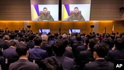 Members of Japan's lower house parliament applaud as Ukrainian President Volodymyr Zelenskyy delivering a virtual address to Japanese lawmakers in Tokyo, March 23, 2022.