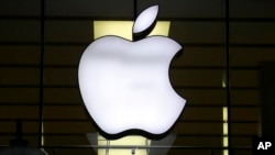 FILE - The Apple logo is illuminated at a store in the city center in Munich, Germany, Dec. 16, 2020.