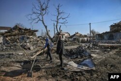 People clean up the debris from destroyed houses after bombardments in the village of Krasylivka, east of Kyiv, March 20, 2022.