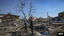 People clean up the debris from destroyed houses after bombardments in the village of Krasylivka, east of Kyiv, March 20, 2022. 