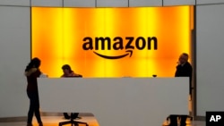 FILE - People stand in the lobby of Amazon offices in New York, Feb. 14, 2019.