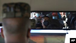 Un soldado, a la izquierda, se sienta en el asiento del conductor de un autobús lleno de pasajeros en San Salvador, El Salvador, el lunes 14 de marzo de 2022. (AP Photo/Salvador Melendez)