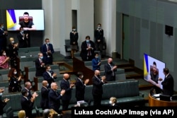 Australian members of Parliament applaud as Ukrainian President Volodymyr Zelenskyy addresses the House of Representatives via a video link at Parliament House in Canberra, Australia, March 31, 2022.