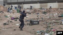 FILE: A member of SAPS shoots rubber bullets to disperse a crowd looting outside a warehouse storing alcohol in Durban on 7.16.2021 in the midst of an ongoing alcohol ban after protestors have clashed with police following a week of unrest in South Africa. 