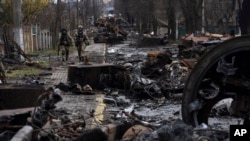 Soldiers walk amid destroyed Russian tanks in Bucha, in the outskirts of Kyiv, Ukraine, Sunday, April 3, 2022.
