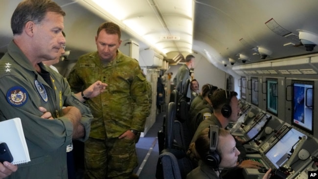 Admiral John C. Aquilino, left, Commander of the U.S. Indo-Pacific Command, looks at videos of Chinese structures on board a US P-8A Poseidon plane flying at the Spratly in the South China Sea on March 20, 2022. (AP Photo/Aaron Favila)