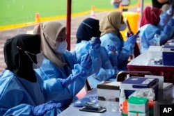 Petugas medis menyiapkan suntikan vaksin COVID-19 Pfizer di Stadion Patriot Candrabhaga, Bekasi, 8 Februari 2022. (Foto: AP)