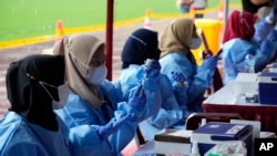 Petugas medis menyiapkan suntikan vaksin Pfizer COVID-19 di Stadion Patriot Candrabhaga Bekasi, Selasa, 8 Februari 2022. (Foto: AP/Achmad Ibrahim)