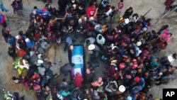 FILE - People lower the remains of Elfego Miranda Diaz into a grave, one of the Guatemalan migrants who was killed near the US-Mexico border in January, at a cemetery in Comitancillo, Guatemala, March 13, 2021.