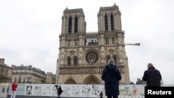 People look at the Notre-Dame de Paris Cathedral as its Emmanuel tenor bell rings to "call for peace in Europe", following Russia's invasion of Ukraine, in Paris, France, March 3, 2022. (REUTERS/Johanna Geron) 