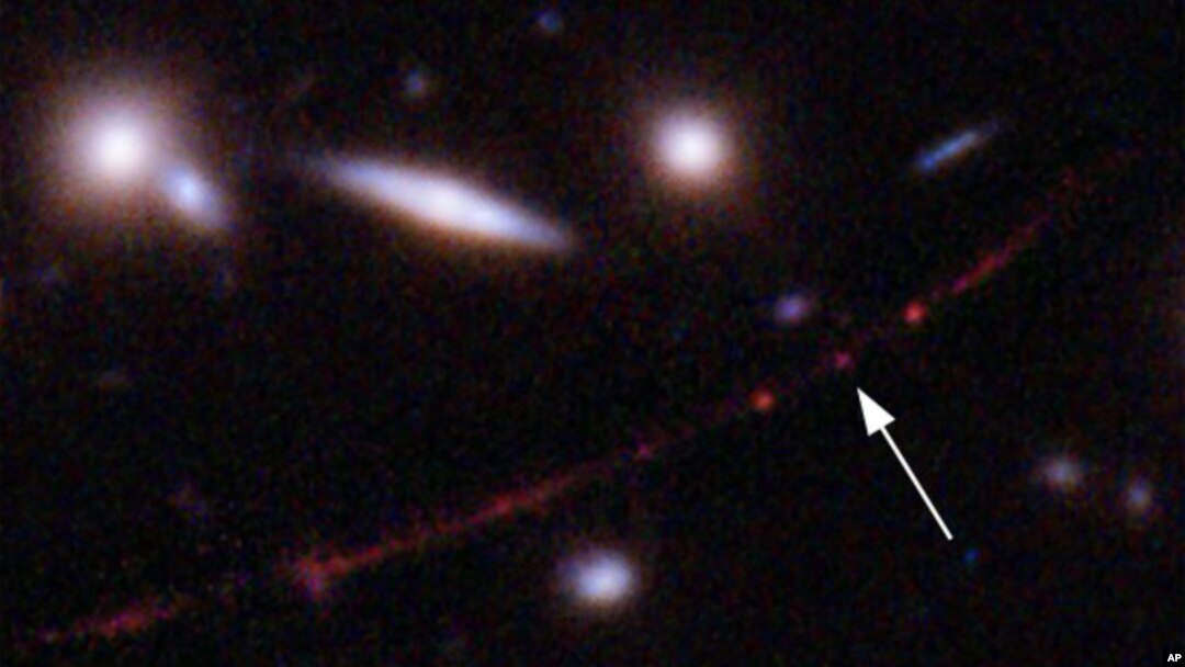 This image made available by NASA on Wednesday, March 30, 2022, shows the star Earendel, indicated by arrow, and the Sunrise Arc galaxy, stretching from lower left to upper right. 